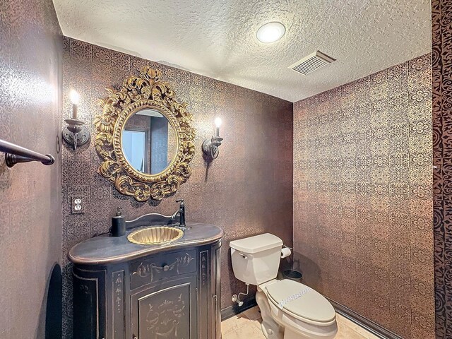 bathroom featuring vanity, toilet, and a textured ceiling