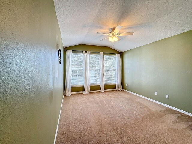 carpeted spare room with ceiling fan, a textured ceiling, and lofted ceiling