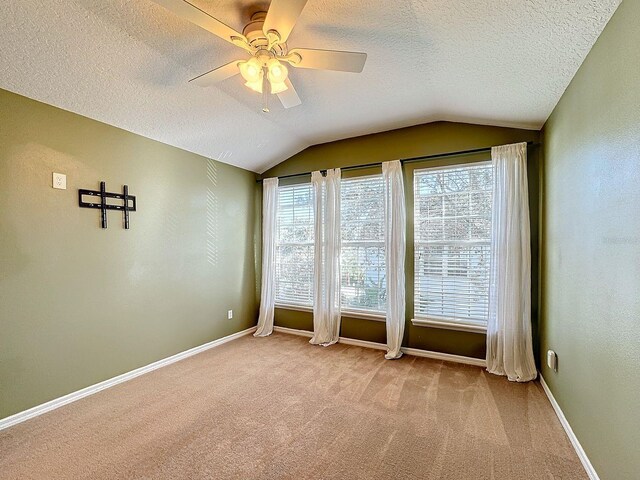 empty room featuring light carpet, a textured ceiling, ceiling fan, and vaulted ceiling