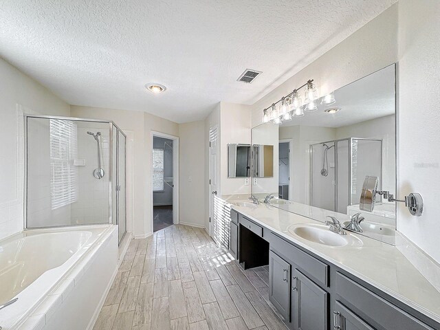 bathroom featuring vanity, a textured ceiling, plus walk in shower, and wood-type flooring