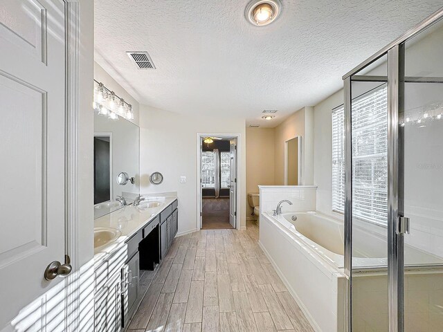 bathroom featuring hardwood / wood-style floors, a textured ceiling, toilet, vanity, and a tub to relax in