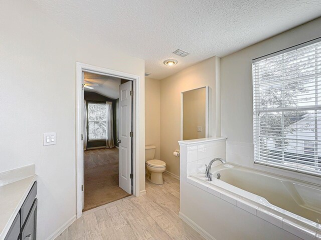 bathroom with a bath, a textured ceiling, toilet, vanity, and hardwood / wood-style flooring