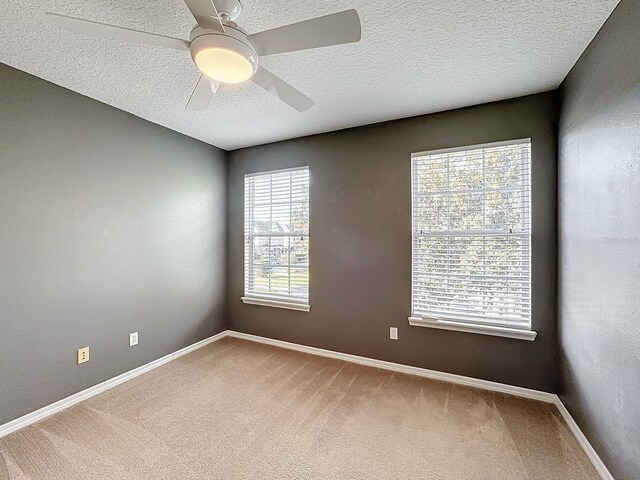 carpeted spare room with a textured ceiling and ceiling fan