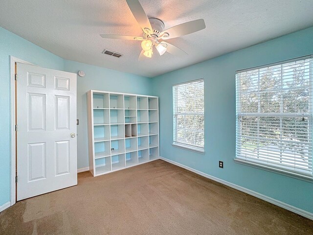 carpeted spare room featuring ceiling fan and a textured ceiling