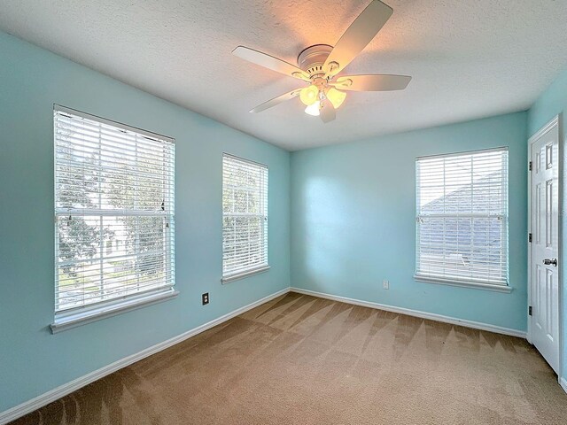 carpeted empty room featuring ceiling fan and a textured ceiling