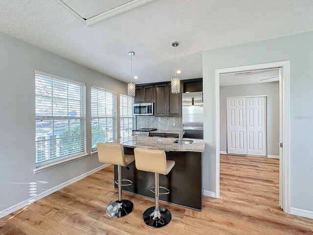 kitchen featuring appliances with stainless steel finishes, tasteful backsplash, light stone countertops, and light hardwood / wood-style floors