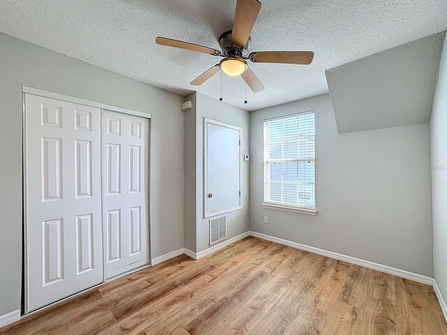 unfurnished bedroom featuring light hardwood / wood-style flooring, a textured ceiling, a closet, and ceiling fan