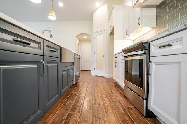 kitchen featuring dark wood-type flooring, tasteful backsplash, decorative light fixtures, and white cabinets