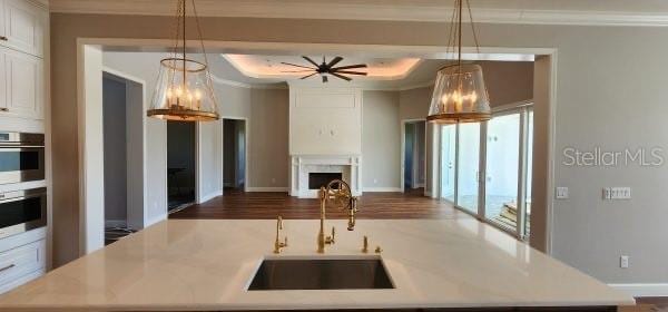 kitchen featuring dark hardwood / wood-style floors, sink, decorative light fixtures, and a center island with sink