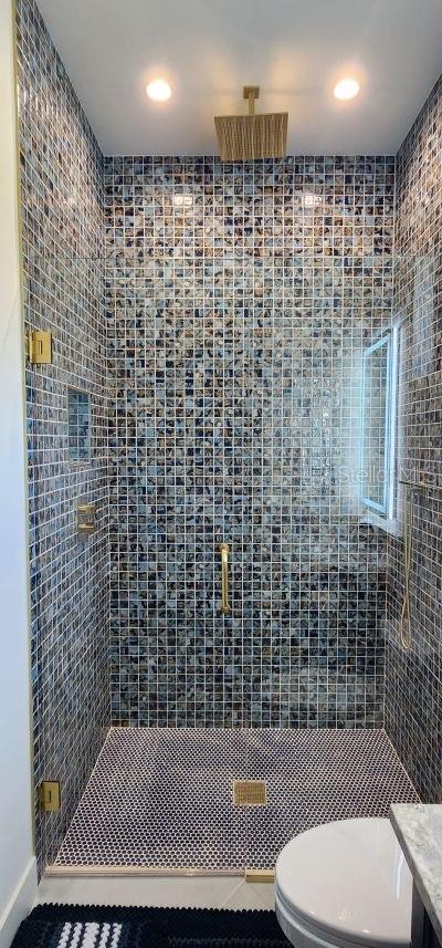 bathroom featuring toilet, vanity, and a tile shower