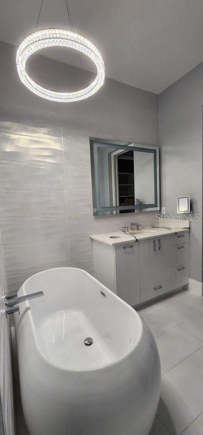 bathroom with vanity, tile patterned floors, tile walls, and a washtub