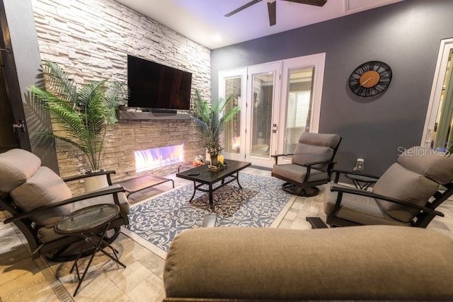 living room featuring ceiling fan and a stone fireplace