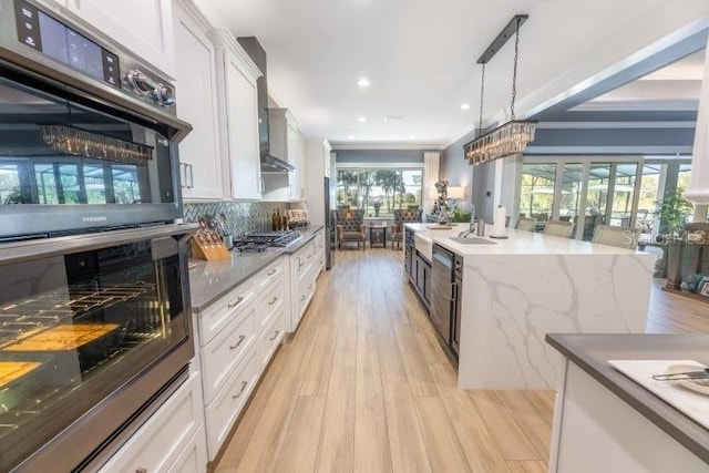 kitchen featuring white cabinets, tasteful backsplash, light hardwood / wood-style flooring, pendant lighting, and double oven