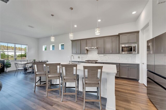 kitchen featuring sink, hardwood / wood-style floors, tasteful backsplash, decorative light fixtures, and stainless steel appliances