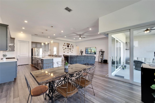 dining room with ceiling fan, sink, and wood-type flooring