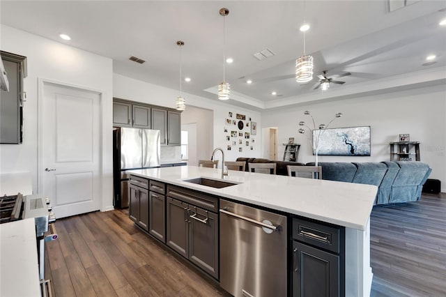 kitchen with visible vents, open floor plan, a tray ceiling, stainless steel appliances, and a sink