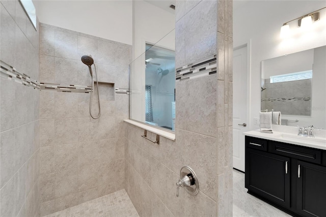 bathroom with a tile shower and vanity