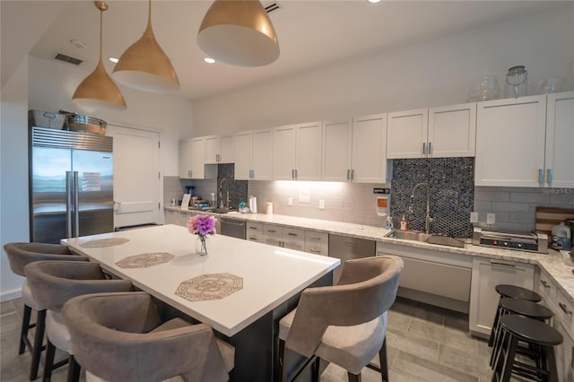 kitchen with white cabinetry, hanging light fixtures, appliances with stainless steel finishes, and sink