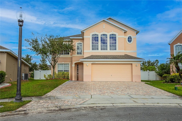 view of property featuring a front yard, a garage, and central air condition unit