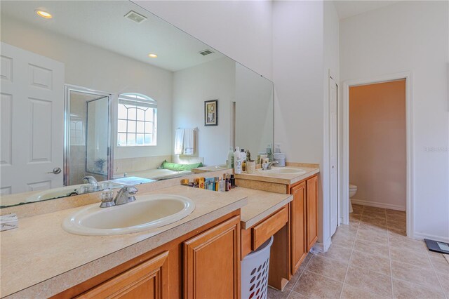 bathroom featuring vanity, a shower with shower door, toilet, and tile patterned flooring