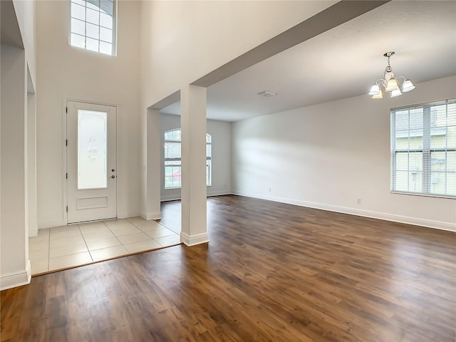 entrance foyer featuring a towering ceiling, light hardwood / wood-style flooring, a chandelier, and a wealth of natural light