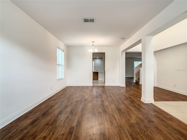 spare room with dark wood-type flooring and a chandelier