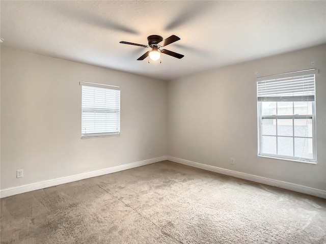 empty room featuring a wealth of natural light, carpet, and ceiling fan