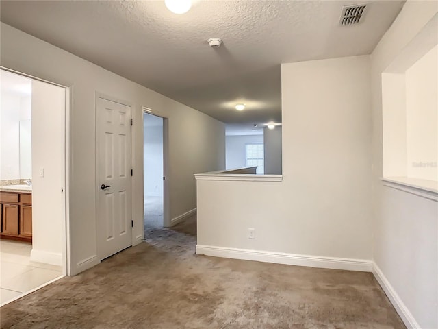 spare room with light carpet, a textured ceiling, and sink