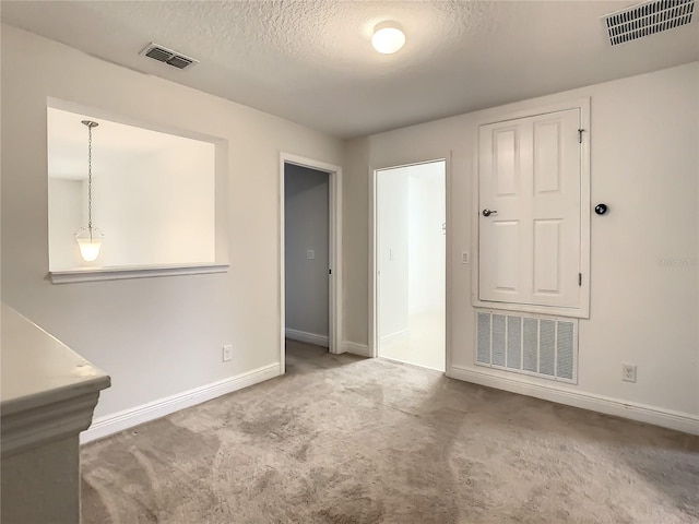 carpeted empty room featuring a textured ceiling