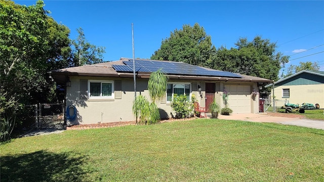 ranch-style house with a front yard, a garage, and solar panels