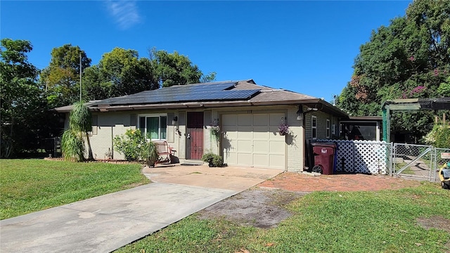 ranch-style home featuring a front yard, solar panels, and a garage