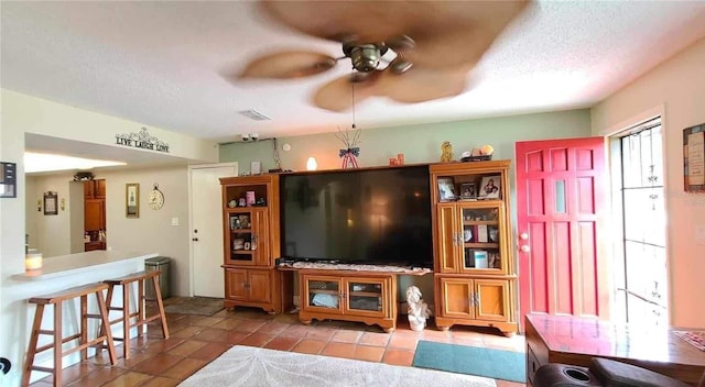 living room with a textured ceiling, tile patterned flooring, and ceiling fan