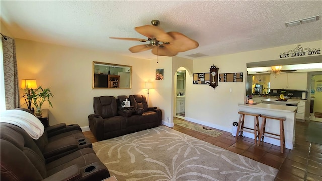 living room with dark tile patterned flooring, ceiling fan, and a textured ceiling