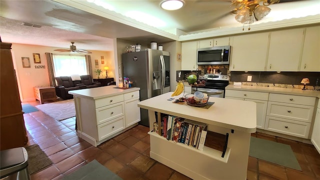 kitchen featuring tasteful backsplash, ceiling fan, dark tile patterned floors, stainless steel appliances, and a center island