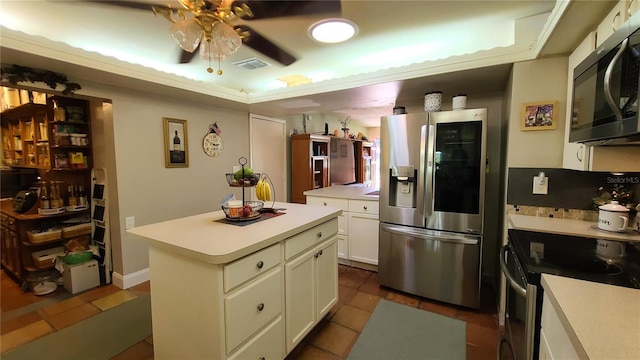 kitchen featuring white cabinets, ceiling fan, appliances with stainless steel finishes, a kitchen island, and dark tile patterned flooring