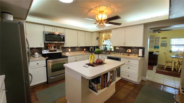 kitchen with a center island, stainless steel appliances, white cabinets, and ceiling fan