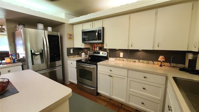 kitchen with white cabinets, stainless steel appliances, sink, and dark tile patterned flooring