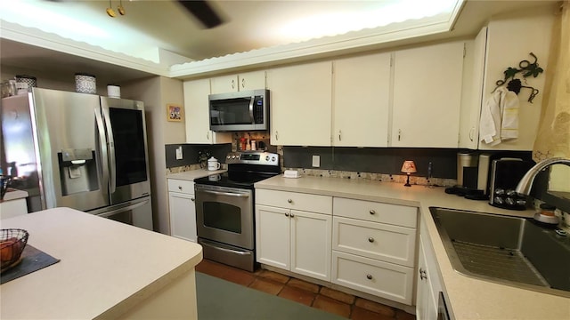 kitchen with dark tile patterned floors, sink, white cabinetry, and stainless steel appliances