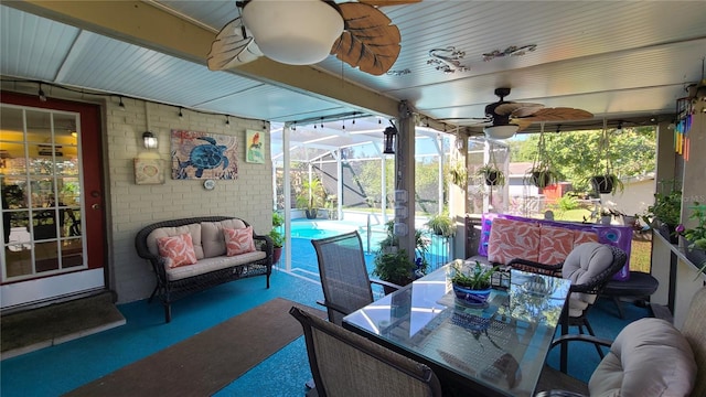 view of patio featuring ceiling fan and glass enclosure