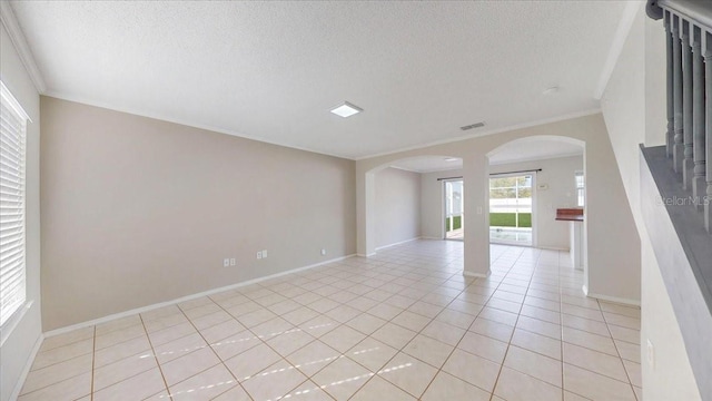 unfurnished room with light tile patterned floors, a textured ceiling, and ornamental molding