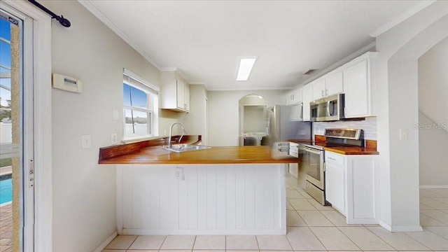 kitchen featuring white cabinets, crown molding, sink, kitchen peninsula, and stainless steel appliances