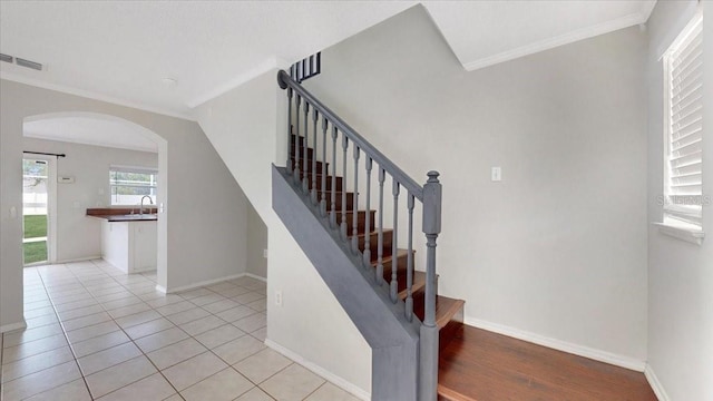 staircase with tile patterned flooring, crown molding, and sink