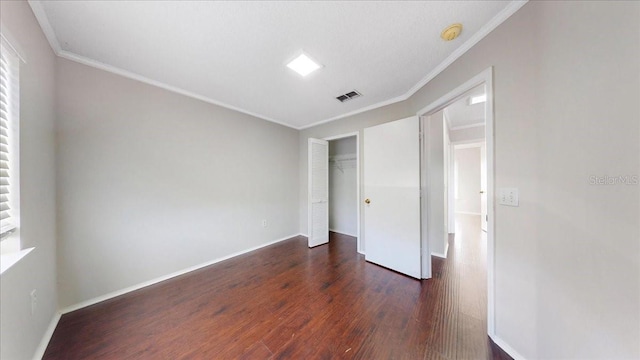 unfurnished bedroom featuring ornamental molding, dark wood-type flooring, and a closet