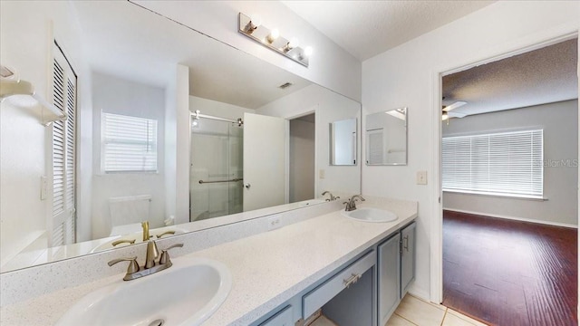 bathroom featuring ceiling fan, vanity, an enclosed shower, and hardwood / wood-style flooring