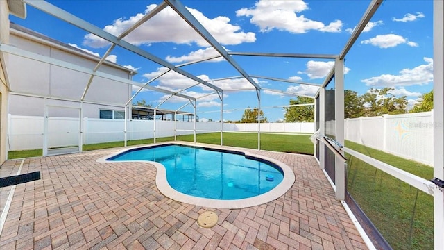 view of swimming pool with glass enclosure, a patio area, and a yard