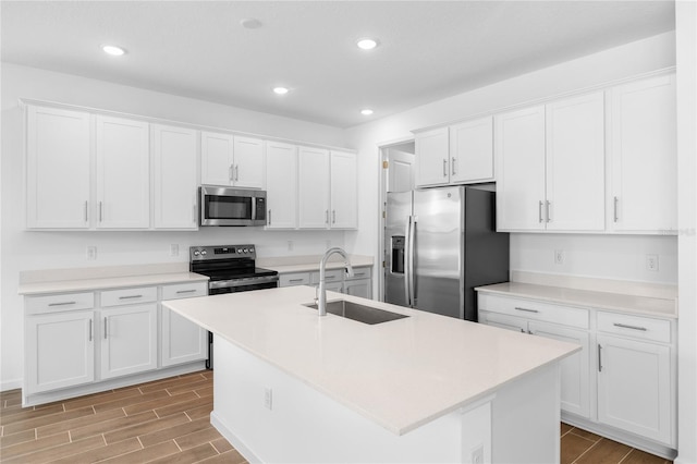 kitchen with white cabinets, stainless steel appliances, a sink, and wood tiled floor