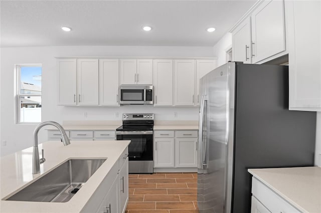kitchen with light wood-style floors, a sink, white cabinets, and stainless steel appliances