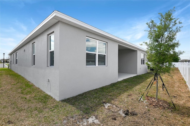 view of property exterior with a yard, fence, and stucco siding