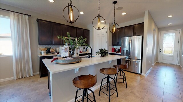 kitchen featuring backsplash, stainless steel fridge with ice dispenser, dark brown cabinetry, and a wealth of natural light