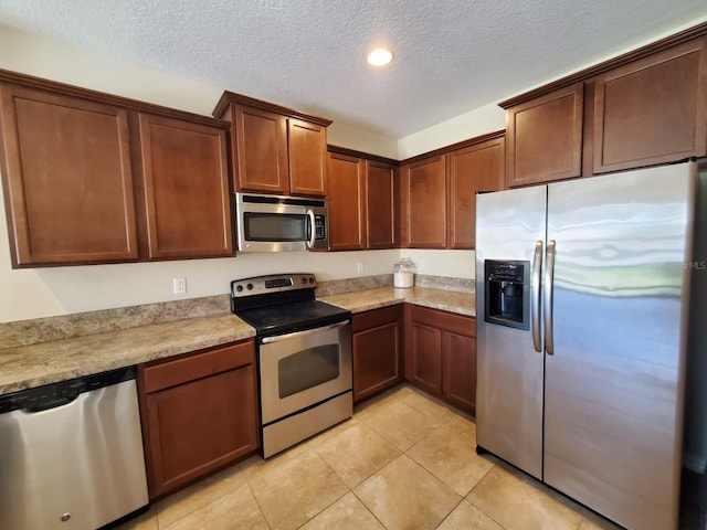 kitchen with appliances with stainless steel finishes, a textured ceiling, and light tile patterned floors